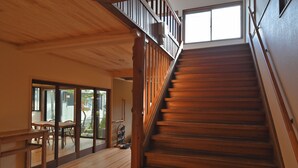 Una escalera de madera con barandilla que lleva a un balcón con vistas al exterior.