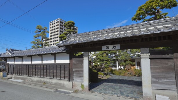 Un edificio japonés tradicional con tejado de tejas y un letrero.