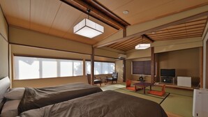 Habitación de hotel con dos camas, televisión y un pequeño espacio de descanso con una mesa y sillas.