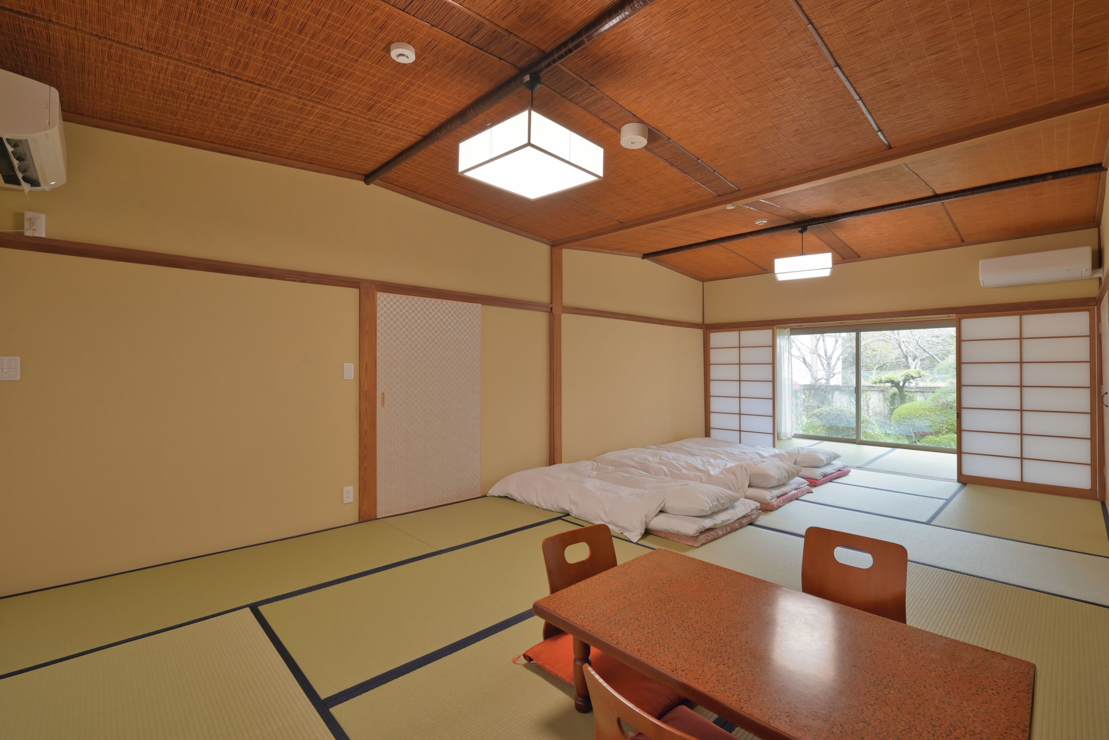 A traditional Japanese room with tatami flooring, a low wooden table, and a futon bed.