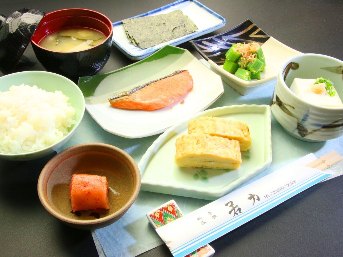 A table with various Japanese dishes including rice, salmon, tofu, and pickled vegetables.