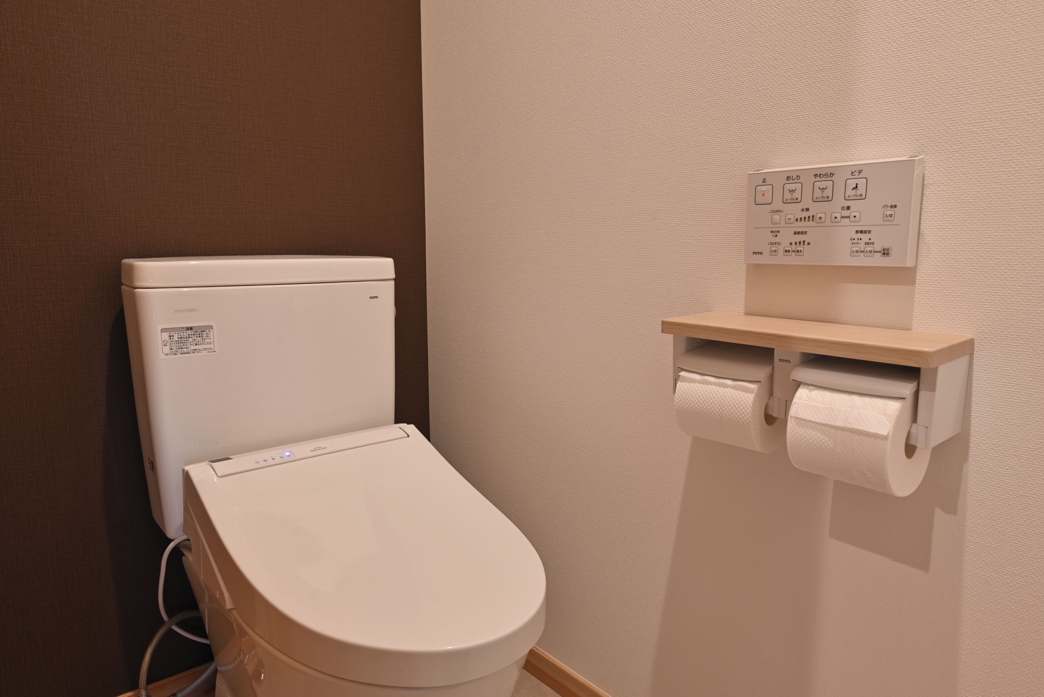Un inodoro con un panel de control y un dispensador de papel higiénico.
