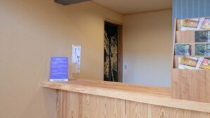 Una recepción con mostrador de madera y un tablón de anuncios con folletos.