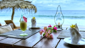 Une table en bois avec un verre, une bougie et des fleurs.