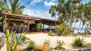 A beachside resort with a covered dining area, outdoor seating, and a view of the ocean. - Good Karma Ayurvedic Resort (Rekawa)