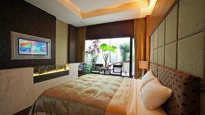 Een moderne hotelkamer met een groot bed, een aan de muur bevestigde televisie en uitzicht op het landschap door een groot raam.