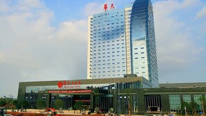 A modern hotel with a prominent sign, a large glass facade, and a clear sky in the background. - Loudi Huatian Hotel (Loudi)