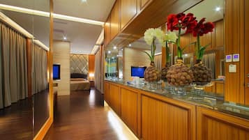 A hotel lobby with wooden paneling, a reception desk, and a seating area with a TV.