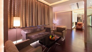 A modern hotel room with a sofa, armchairs, a glass coffee table, and a large window with curtains. - Spring Hotel (Taichung)