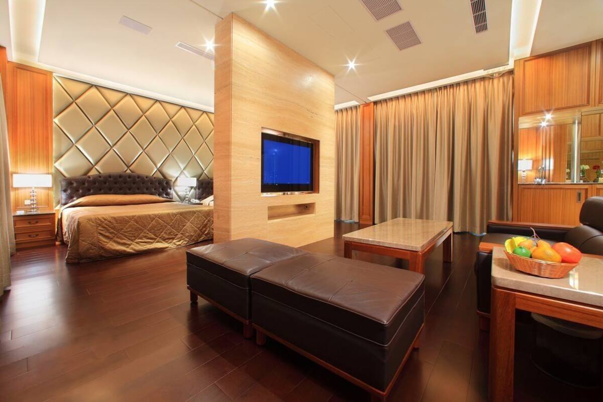 Quarto de hotel moderno com uma cama grande, uma televisão, uma mesa pequena e um espaço para sentar.