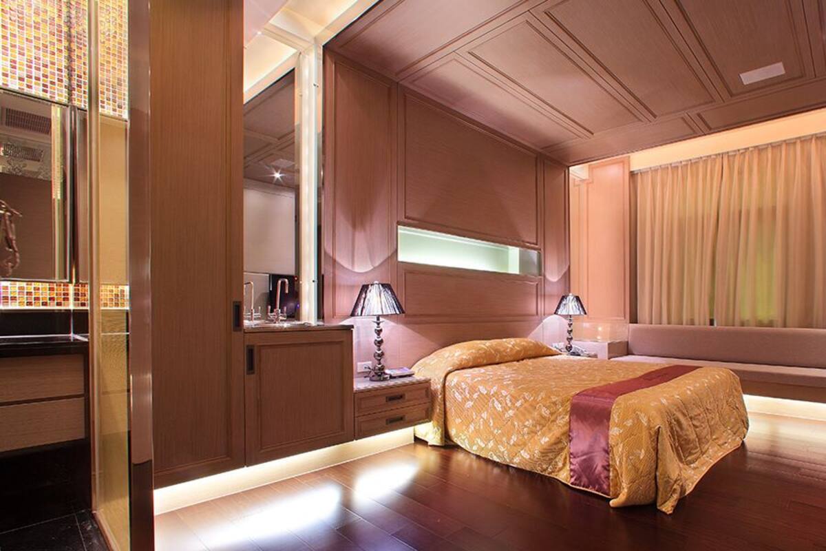 Quarto de hotel moderno com uma cama grande, mesas de cabeceira, uma TV e uma janela com cortinas.