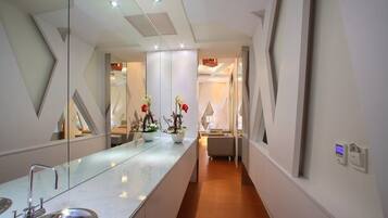 A modern bathroom with a large mirror, a sink, and a potted plant.