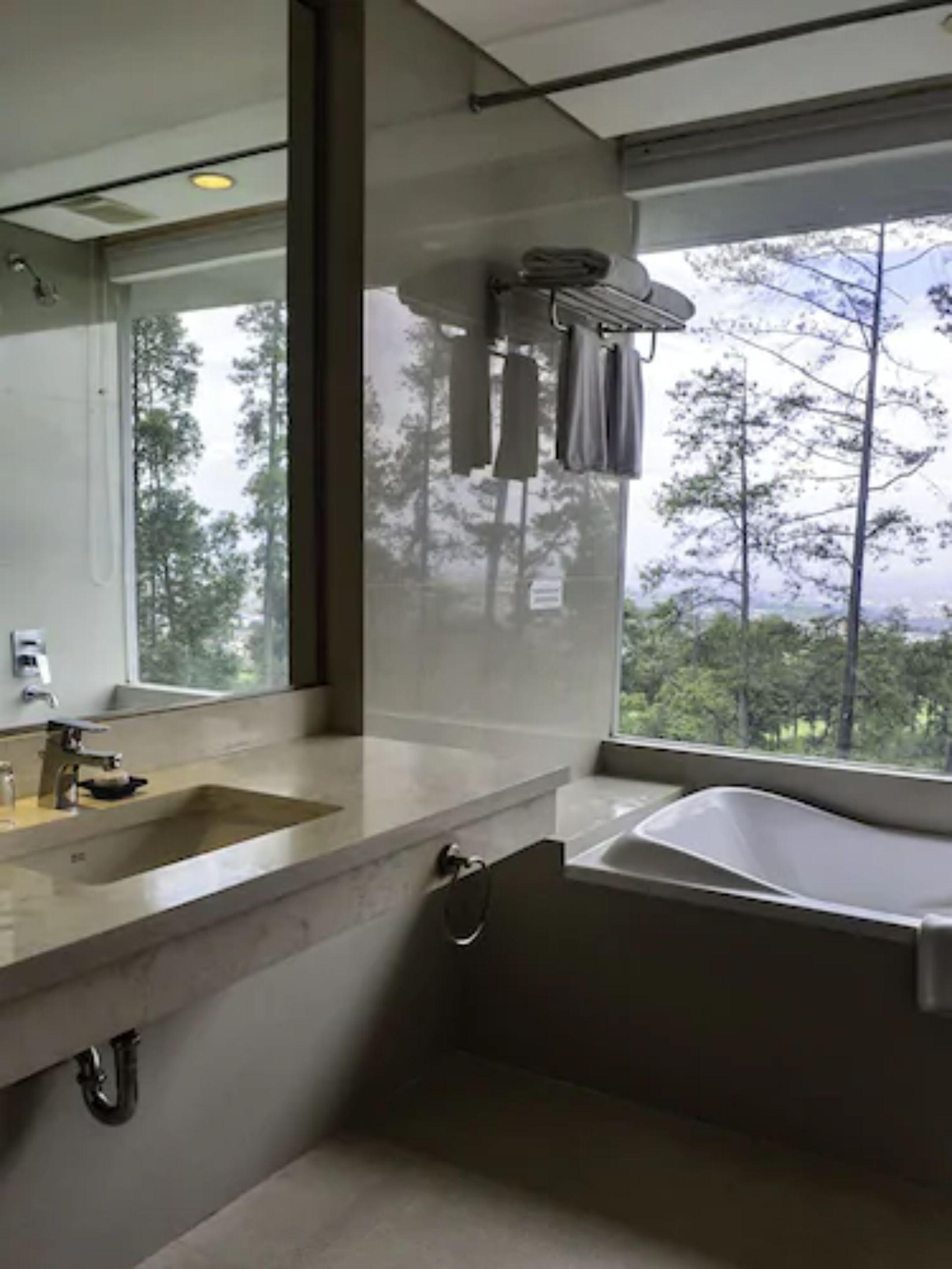 A modern bathroom with a large window, a bathtub, and a sink.