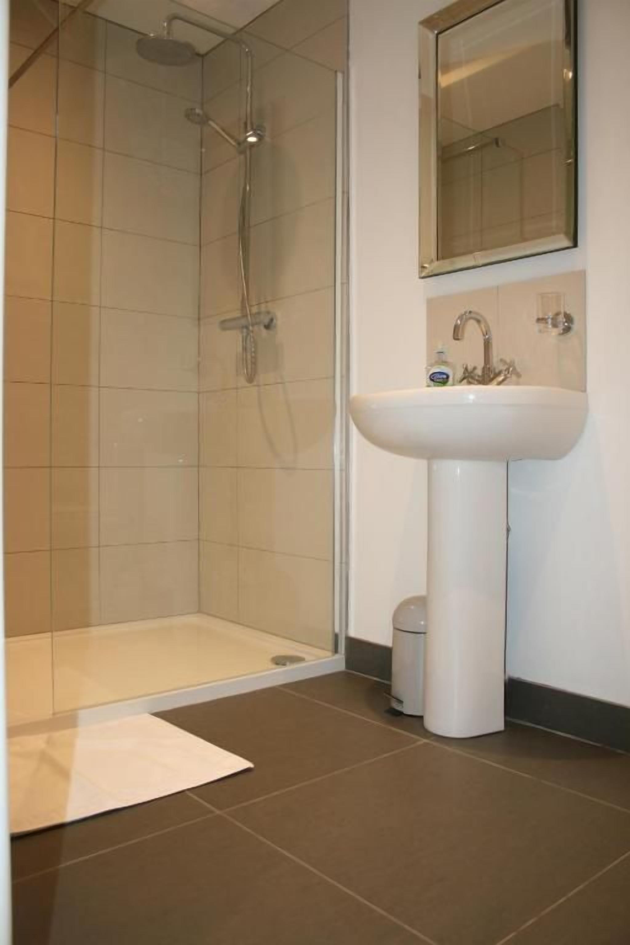 A bathroom with a shower, a sink, and a mirror.