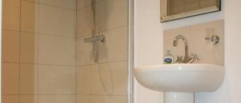 A bathroom with a shower, a sink, and a mirror.