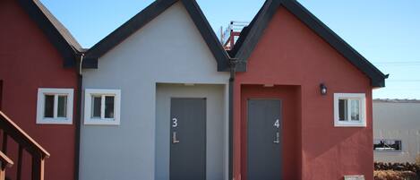 A two-story building with a red and white facade, numbered doors 3 and 4, and a small outdoor seating area.