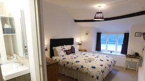 A bedroom with a bed, bedside table, lamp, window, and a view of the outside. - Middletown Farmhouse B&B (Okehampton)