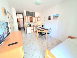 A compact living space with a kitchenette, a dining area, and a bed.