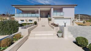 Een modern huis met twee verdiepingen, een overdekte veranda, een garage en een aangelegde oprit.