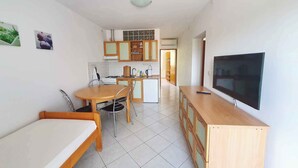 A compact kitchen with a dining area, a TV, and a small refrigerator.