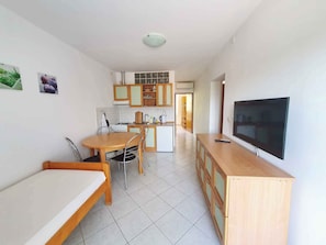 A compact kitchen with a dining area, a TV, and a small refrigerator.