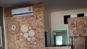 A room with a bed, a wall-mounted air conditioner, decorative wall art, and a window with a green frame. - Aiem Sa Ard Resort (Koh Lan)