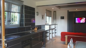 A modern kitchen with black cabinets, a built-in oven, and a window with blinds. - Beautiful ground floor villa with swimming pool, Le Pradet (Var)   (Le Pradet)