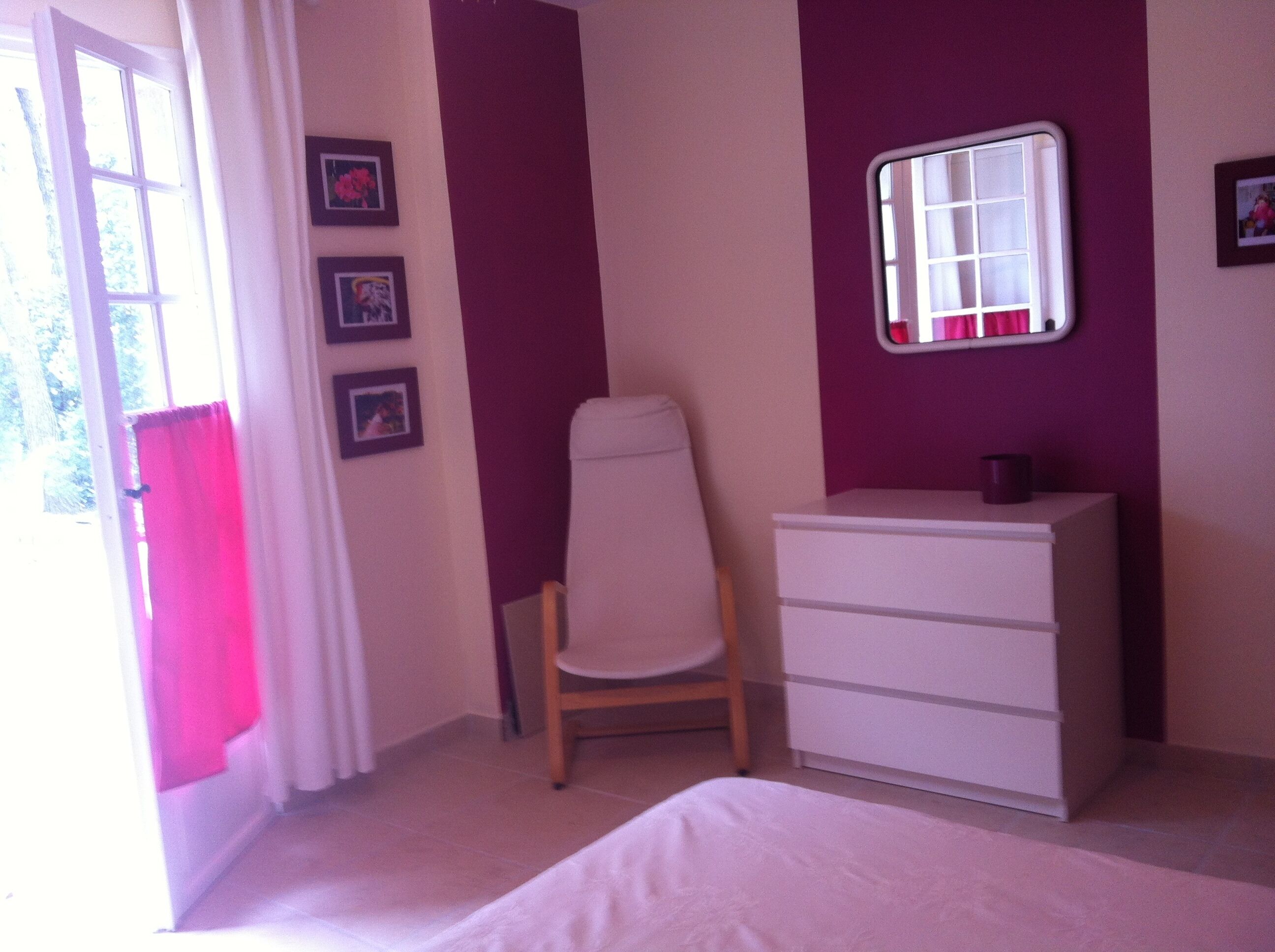 Une chambre à coucher avec un lit, une commode, une chaise et une fenêtre avec un miroir.
