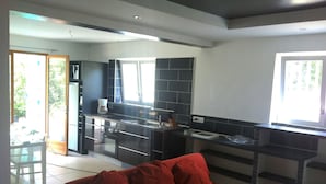 A modern kitchen with dark countertops and a red sofa in the living area. - Beautiful ground floor villa with swimming pool, Le Pradet (Var)   (Le Pradet)