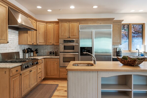 A modern kitchen with wooden cabinets, stainless steel appliances, and a large island with a sink. - Hot Tub, Great Deck, Hiking/Fishing Close! (Durango)