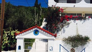A white building with a red roof, a car parked in front, and a no parking sign. - Daskalio Resort Adamis (Lavreotiki)
