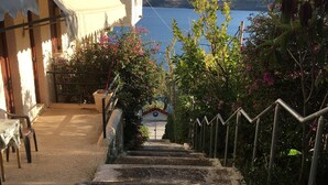 A view of a coastal area with a staircase leading to a building, a clear sky, and a body of water in the distance. - Daskalio Resort Adamis (Lavreotiki)