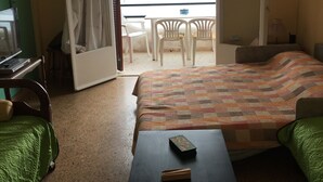 A hotel room with a bed, a desk, a chair, and a balcony with a view of the water. - Daskalio Resort Adamis (Lavreotiki)