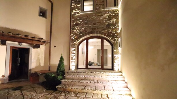 A stone staircase leading to a wooden door with a glass panel, surrounded by a stone wall and a small potted plant. - Il Borgo di Villa Cellaia (Dicomano)