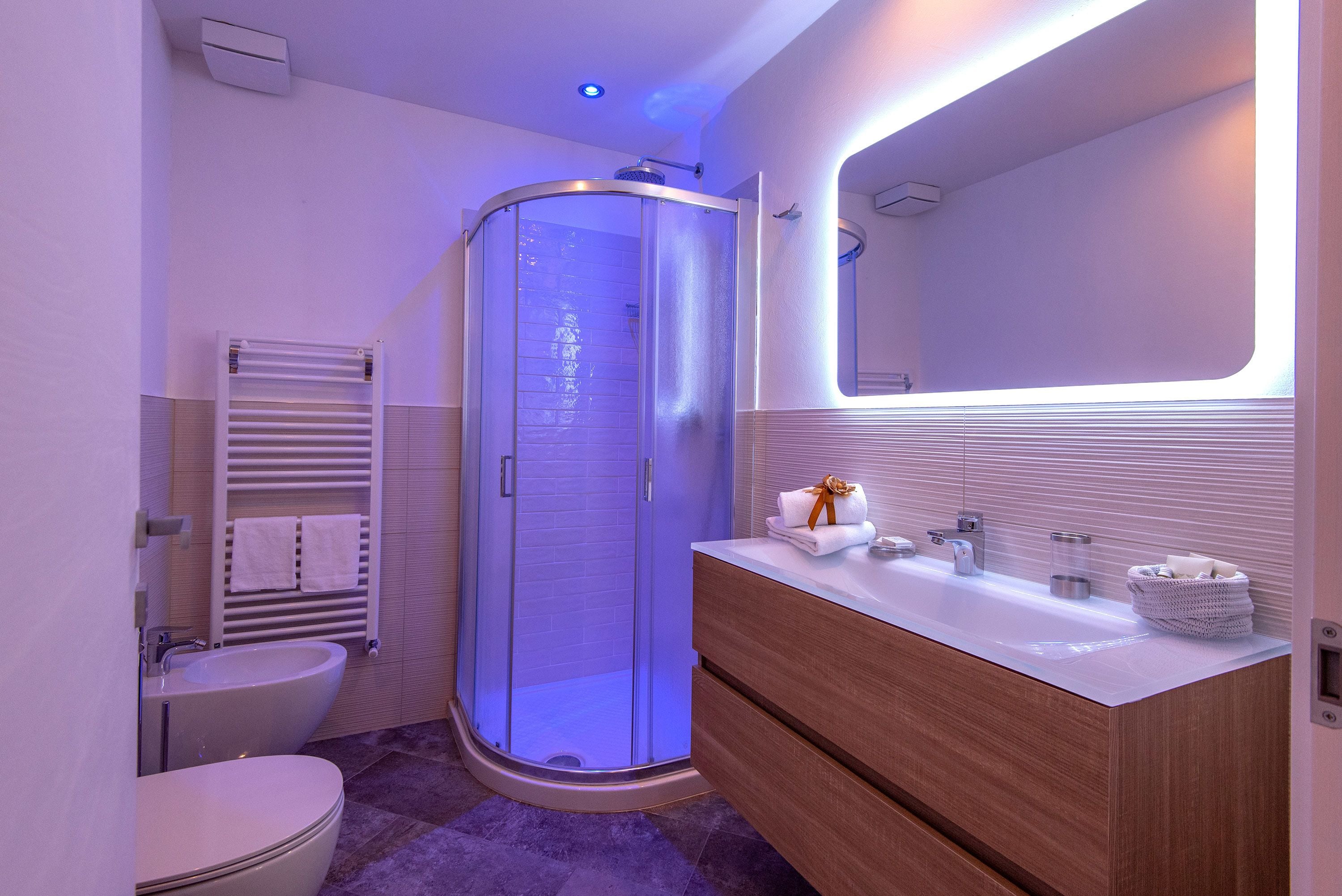 A modern bathroom with a glass-enclosed shower, a wooden vanity, and a white sink.
