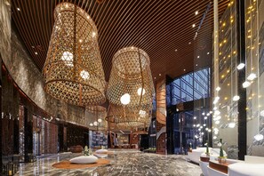 Een ruime lobby met hoge plafonds, gedetailleerde houten spijlenconstructies en moderne verlichtingsarmaturen.