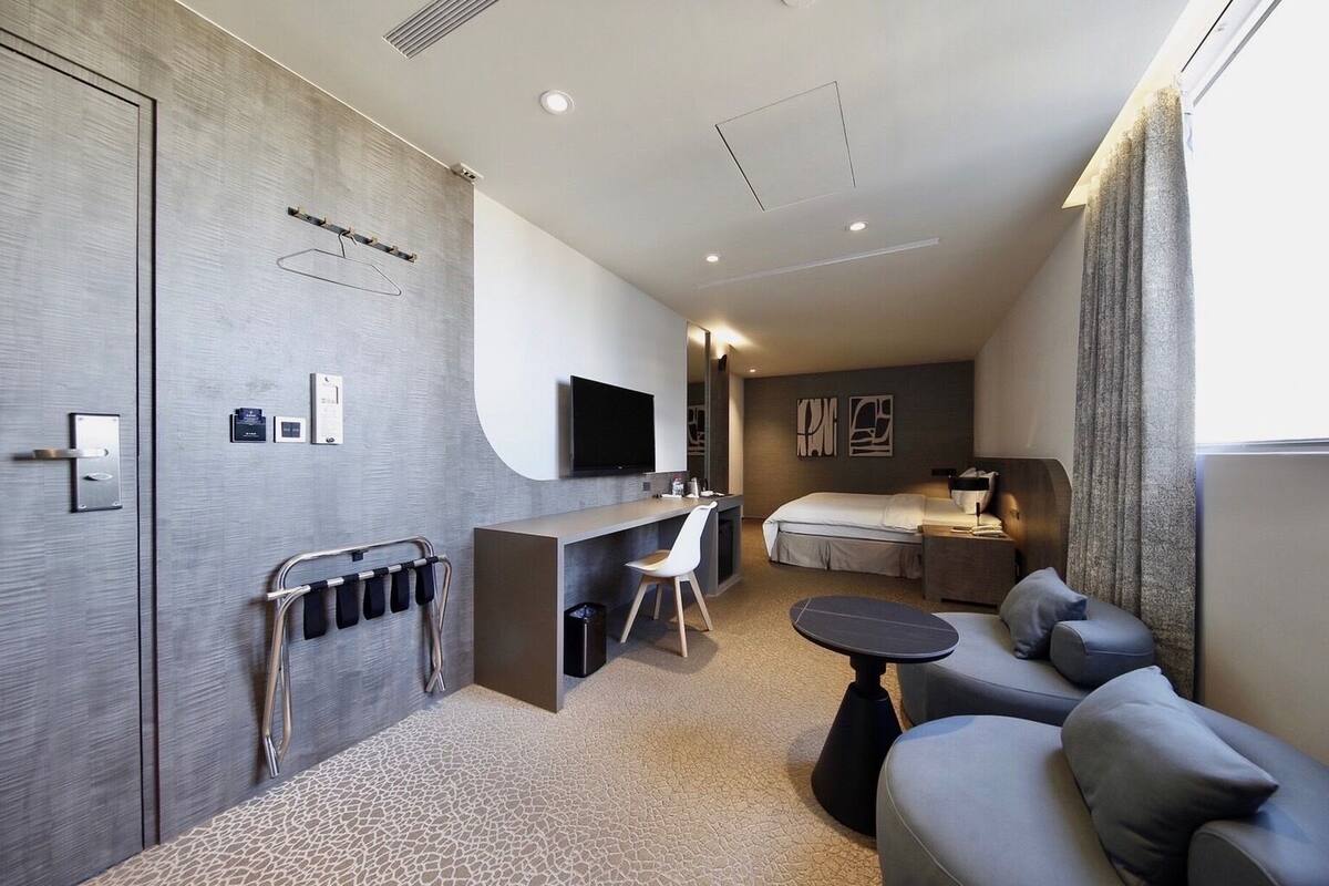 Une chambre d’hôtel moderne équipée d’un lit, d’un canapé, d’un bureau et d’une télévision.