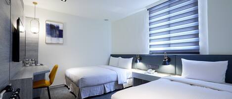 Habitación de hotel con dos camas, un escritorio, una silla, un cuadro y una ventana con persianas.