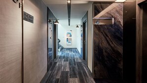 A modern hotel hallway with a marble wall, a wooden floor, and a sign indicating room numbers. - Haifu Hotel & Suites (Jincheng)
