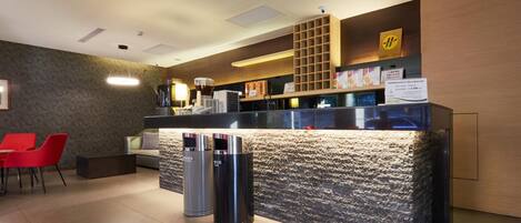 A reception area with a stone counter, red chairs, and a coffee machine.