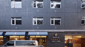 A modern building with a grey facade, multiple windows, and a sign for Haifu Hotel & Suites. - Haifu Hotel & Suites (Jincheng)