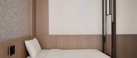 A modern hotel room with a bed, a bedside table, and a large window.