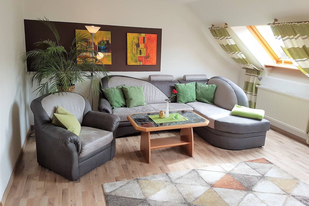 Una sala de estar moderna con un sofá gris, sillones, una mesa de centro y un cuadro grande en la pared.