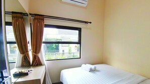 A hotel room with a bed, a desk, and a window with curtains. - Villa Batu 2 kamar 5 dekat Museum Angkut (Batu)