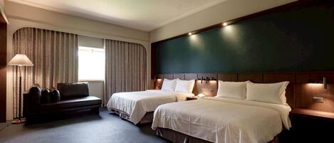 A hotel room with two beds, a sofa, a lamp, and curtains.