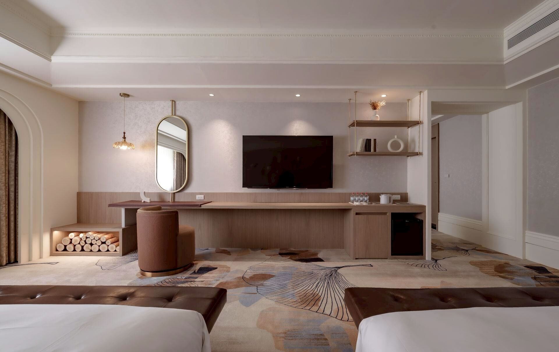A modern hotel room with a large bed, a desk with a mirror, a flat-screen TV, and a small seating area.
