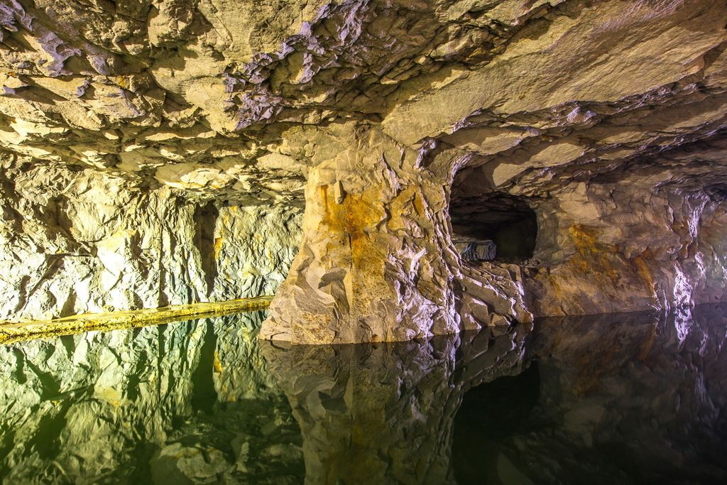 A cave interior with natural rock formations and a reflective water surface.