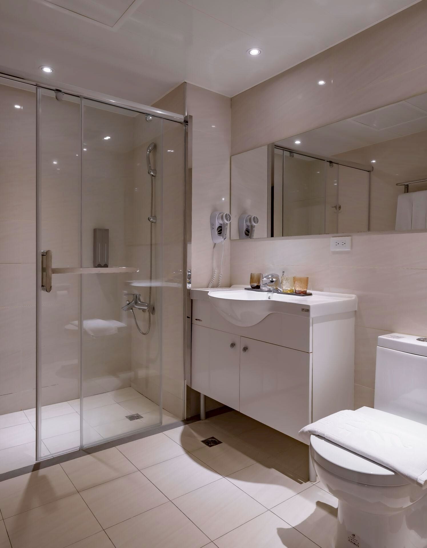 Un baño moderno con cabina de ducha de vidrio, un lavamanos blanco y un inodoro.