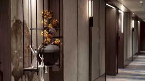 A hallway with a marble wall, a black vase with dried flowers, and a white sculpture. - Haifu Garden Hotel (Jinsha)