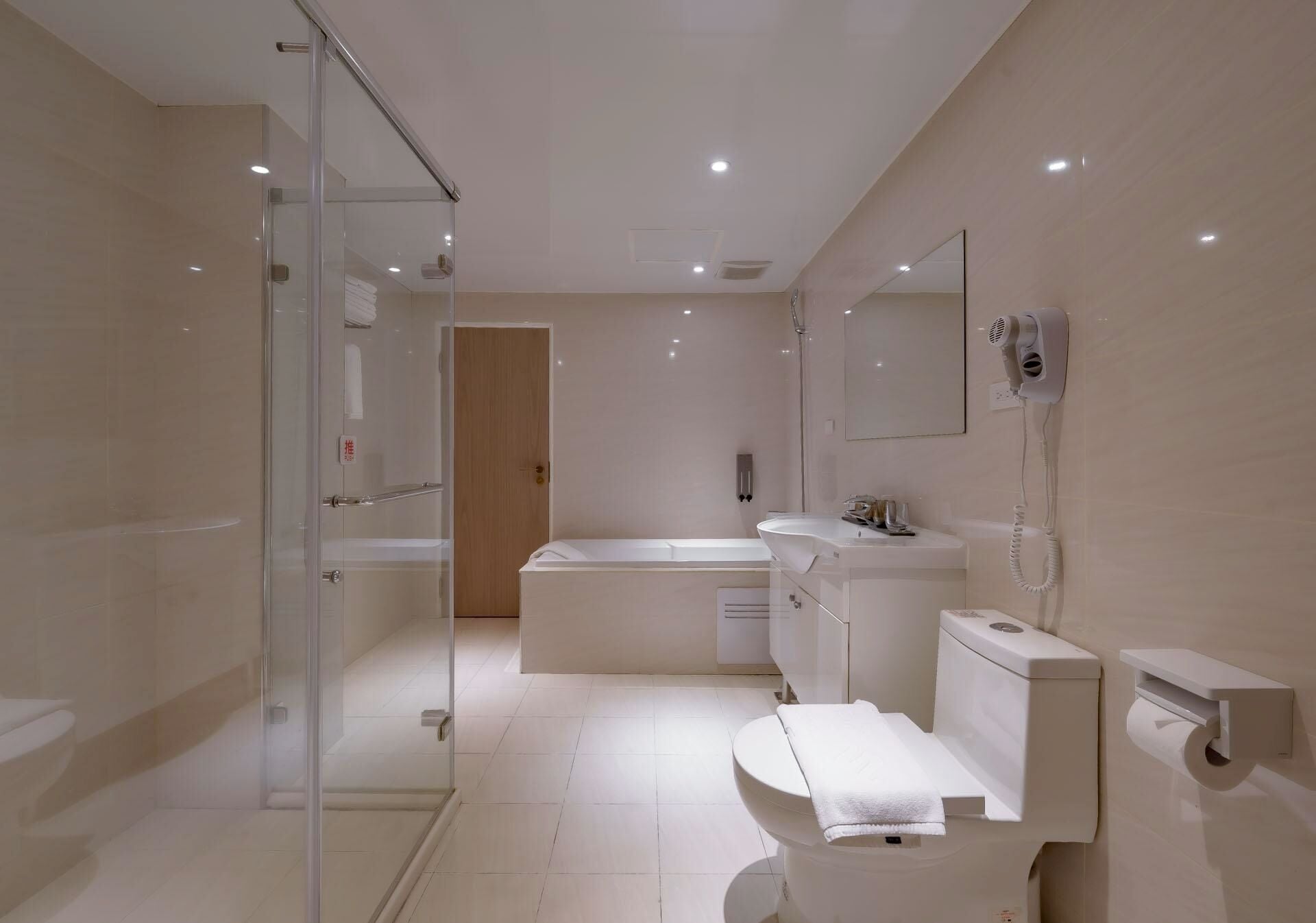 Un baño moderno con cabina de ducha de vidrio, bañera, inodoro y tocador con espejo.